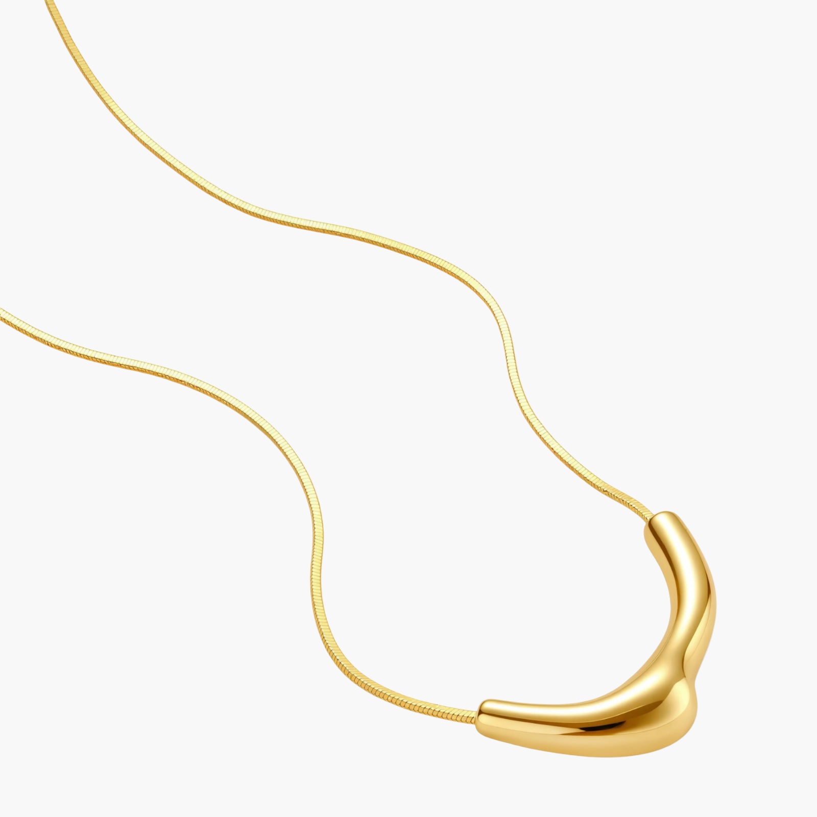 Minimalist gold-plated curved pendant necklace on delicate chain against cream background, showing adjustable length