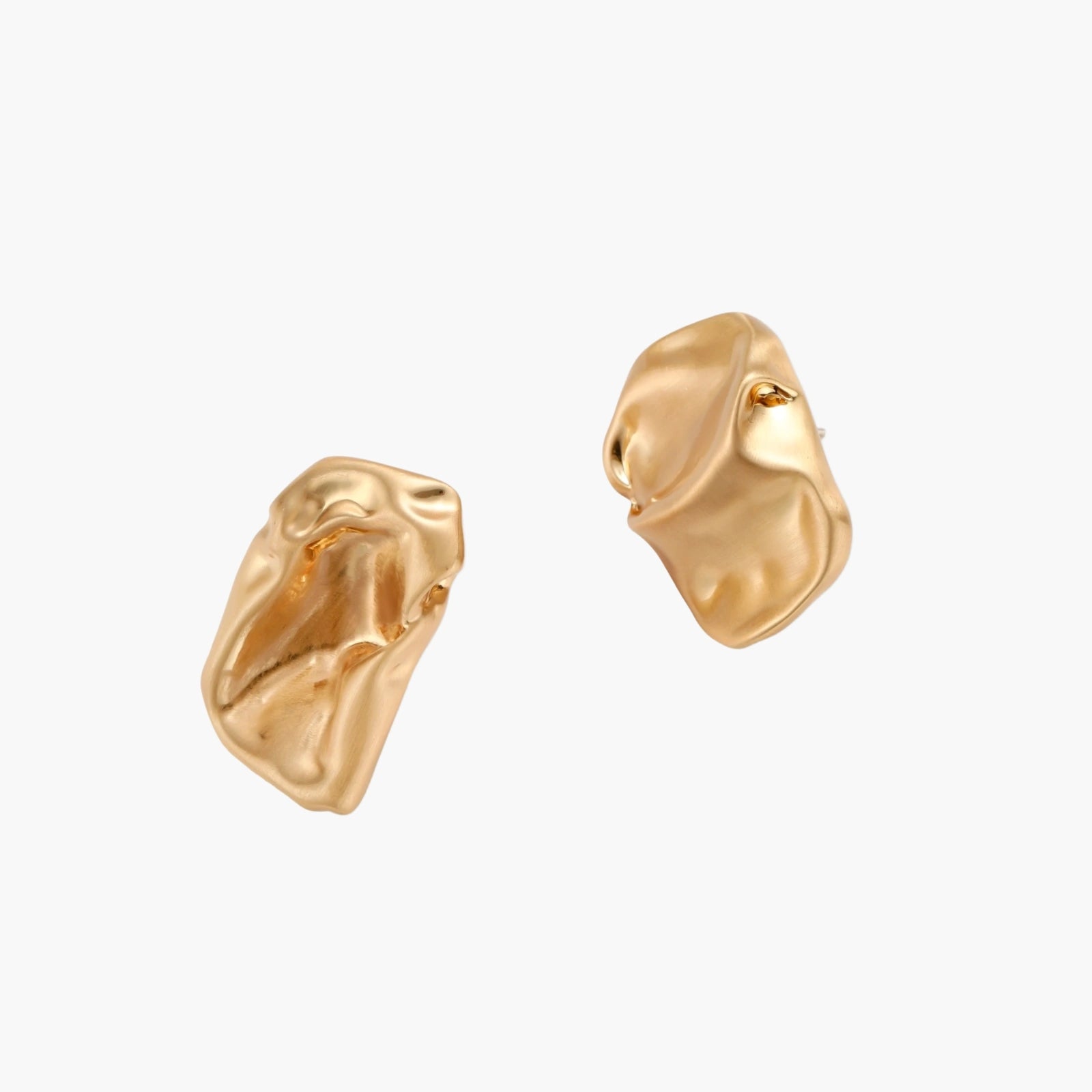 Sculptural gold-toned jewelry set with organic fluid shapes including earrings and layered chain necklace on cream background.