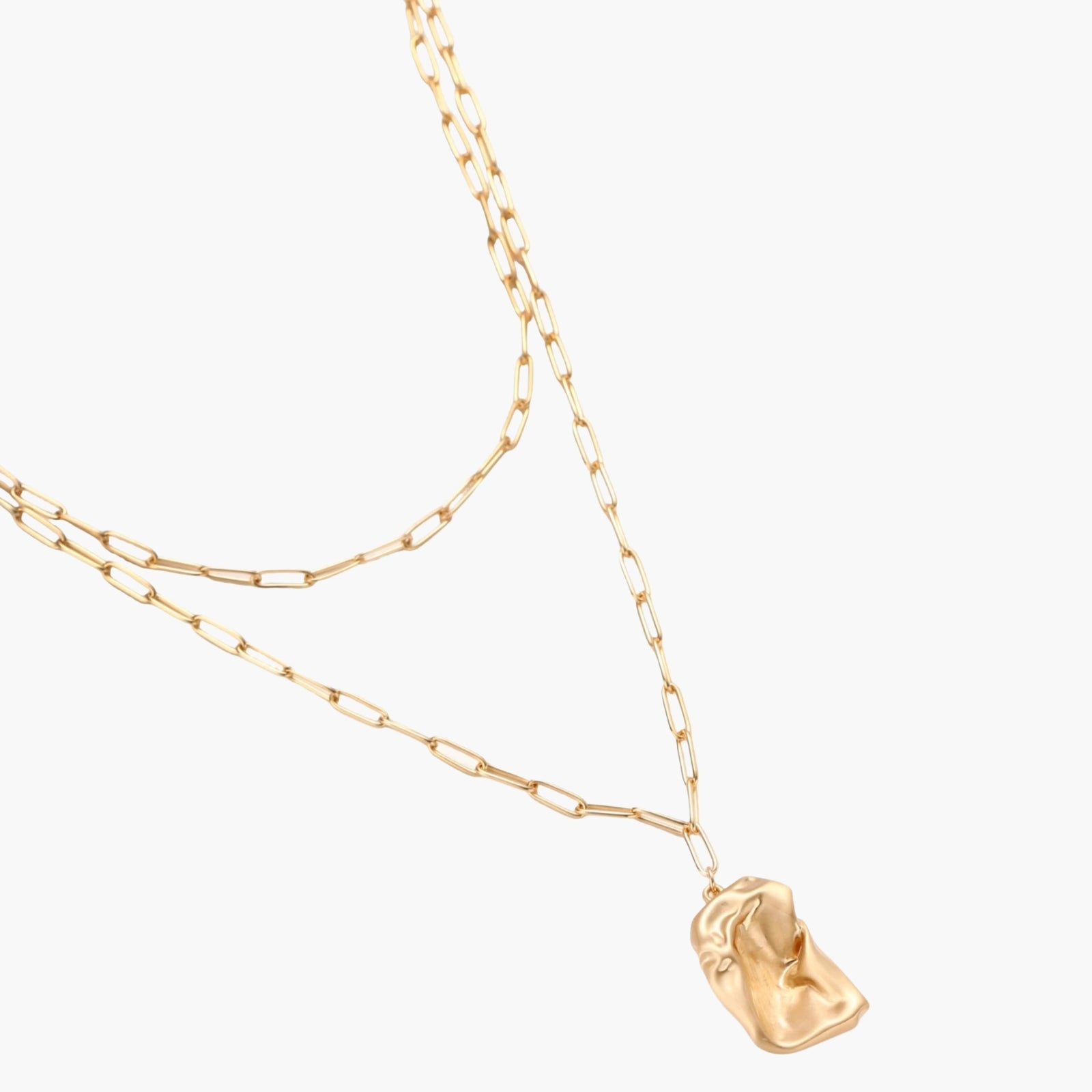 Sculptural gold-toned jewelry set with organic fluid shapes including earrings and layered chain necklace on cream background.