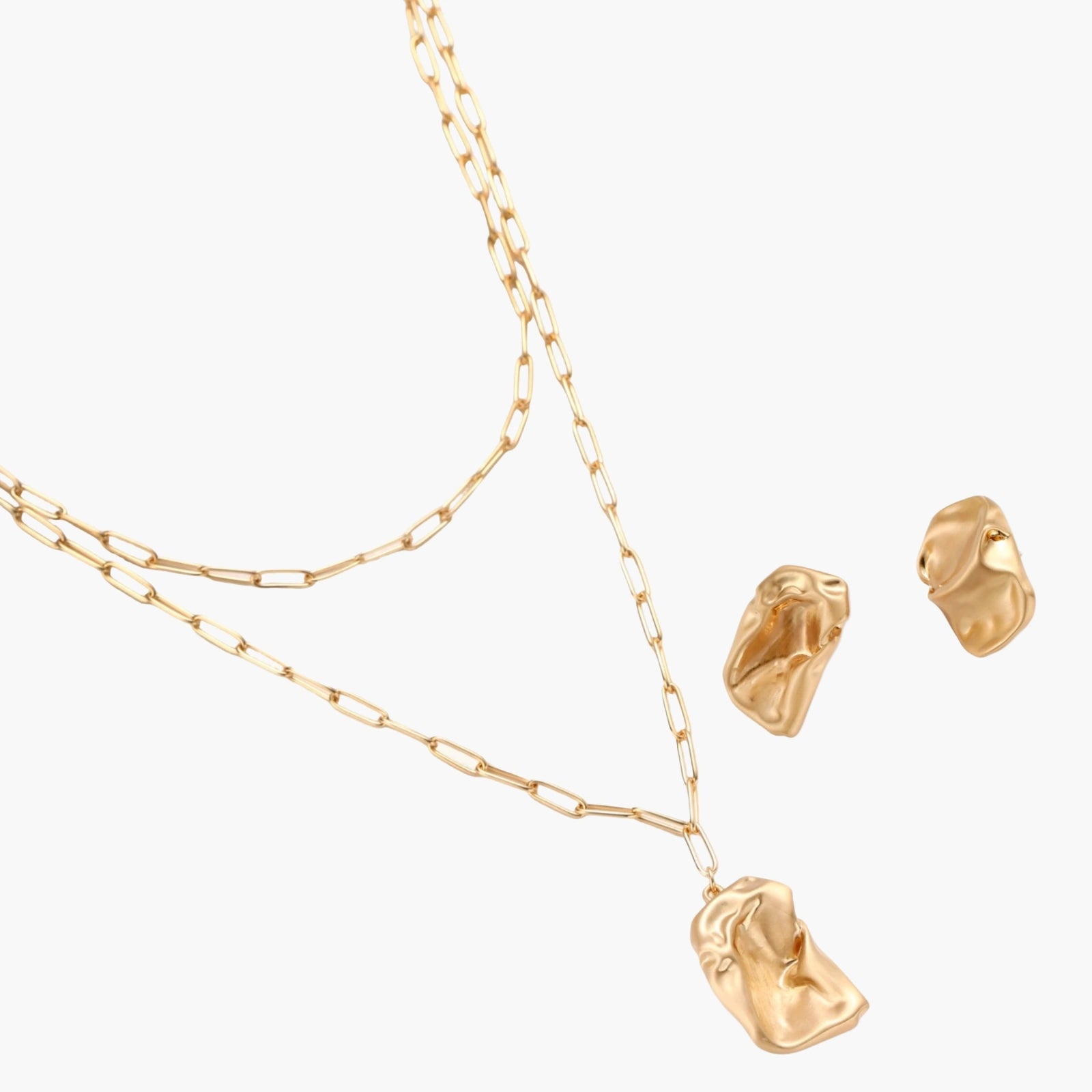 Sculptural gold-toned jewelry set with organic fluid shapes including earrings and layered chain necklace on cream background.
