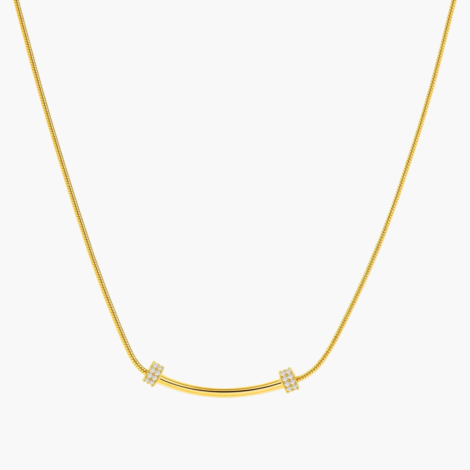 Delicate gold-plated necklace with curved bar pendant and crystal accents on snake chain against cream background.